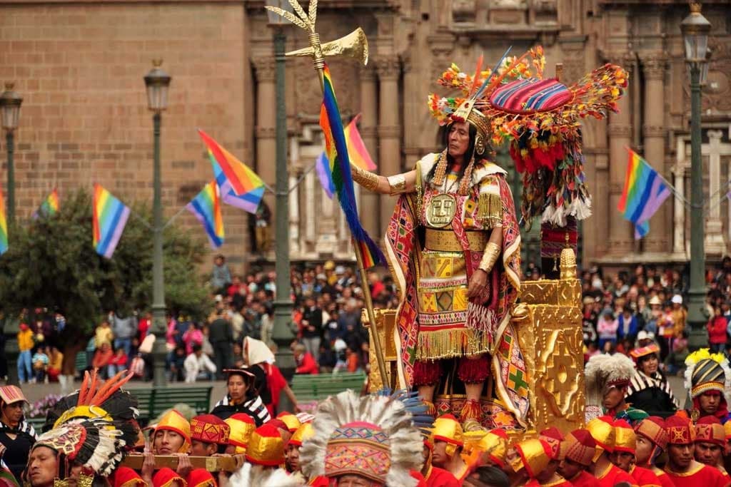 Inca emperor on a ceremonial litter at Inti Raymi in Cusco, Peru, with golden costumes and crowds in Plaza de Armas
