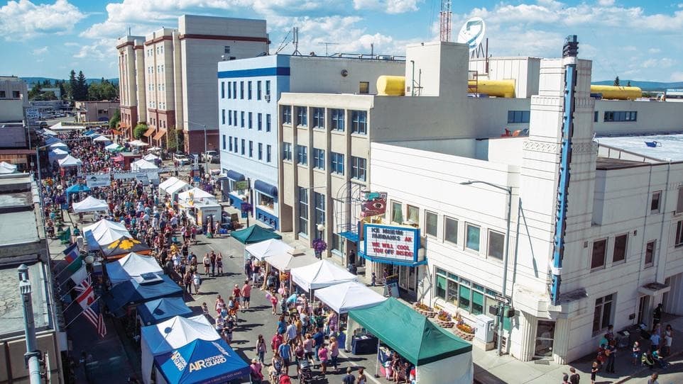 Aerial view of crowds and vendor tents on a downtown Fairbanks street during the Midnight Sun Festival under daylight