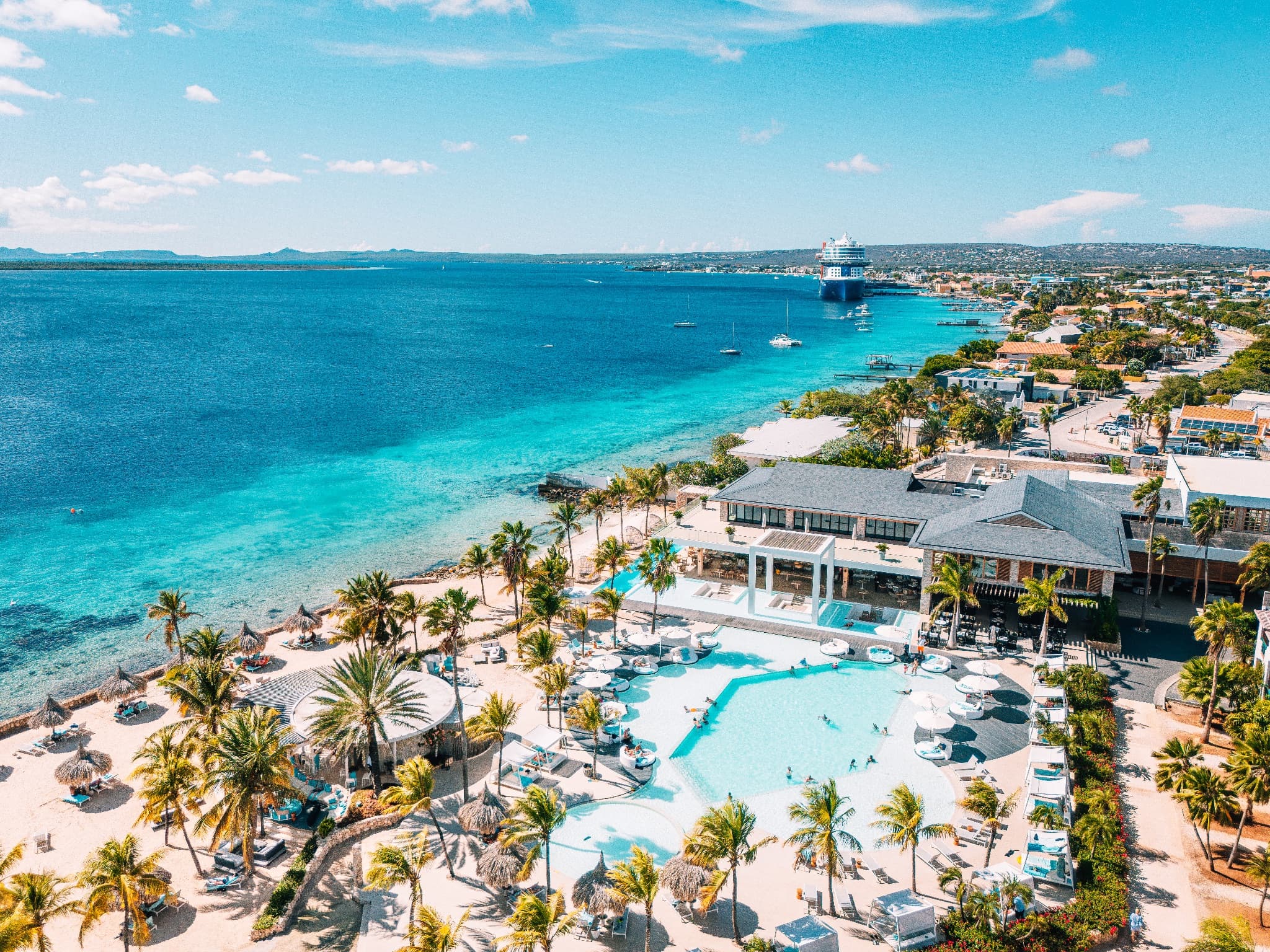 Aerial view of a Bonaire waterfront resort with turquoise Caribbean water and palm trees