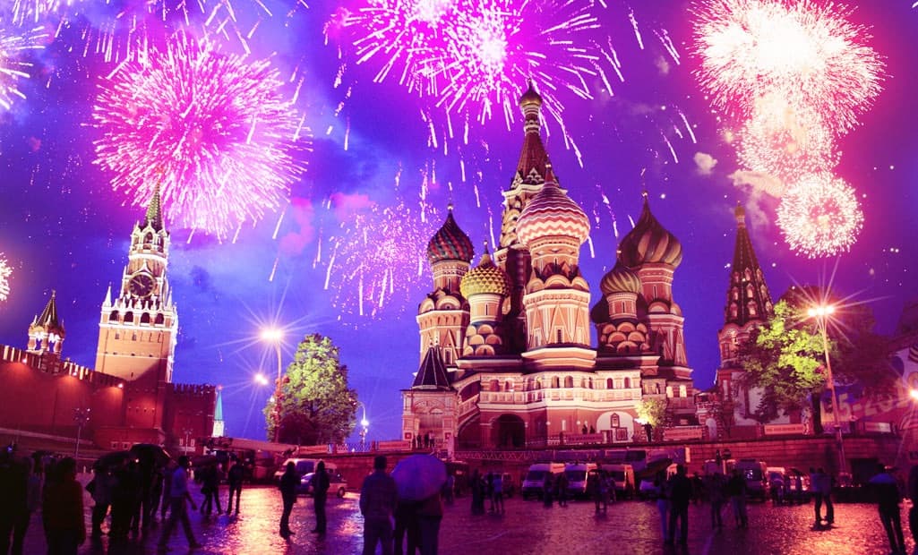 Fireworks over an illuminated cathedral and crowded plaza during a White Nights summer celebration in Russia